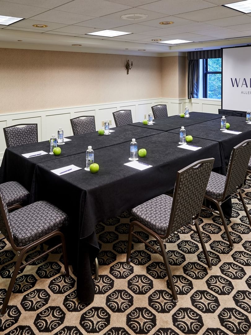 Set up a long table facing the projector screen in the Sullivan Room at Warwick Allerton Chicago