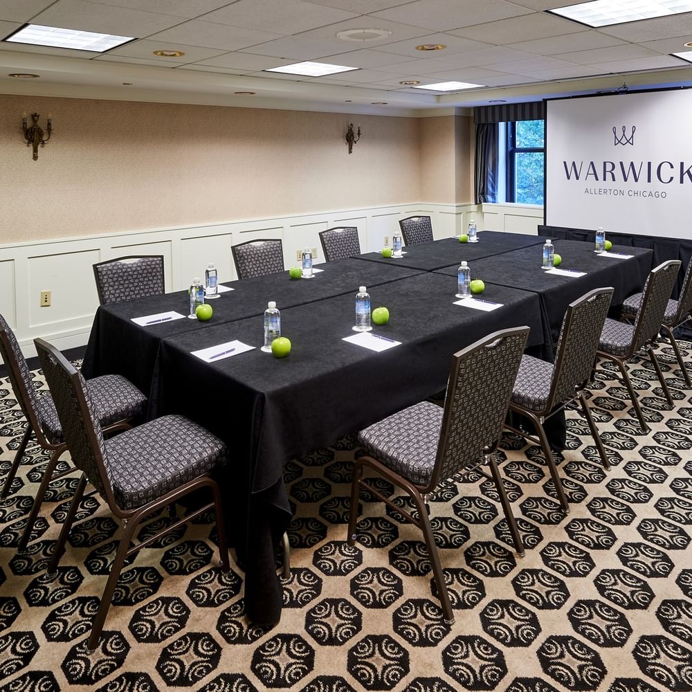 Set up a long table facing the projector screen in the Sullivan Room at Warwick Allerton Chicago