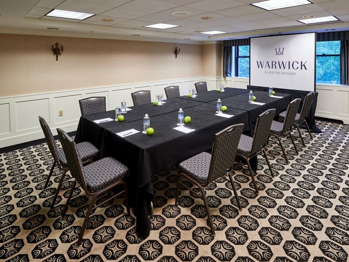 Set up a long table facing the projector screen in the Sullivan Room at Warwick Allerton Chicago