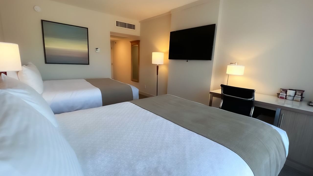 Guest room with two queen beds, desk, chair, tv, lamps