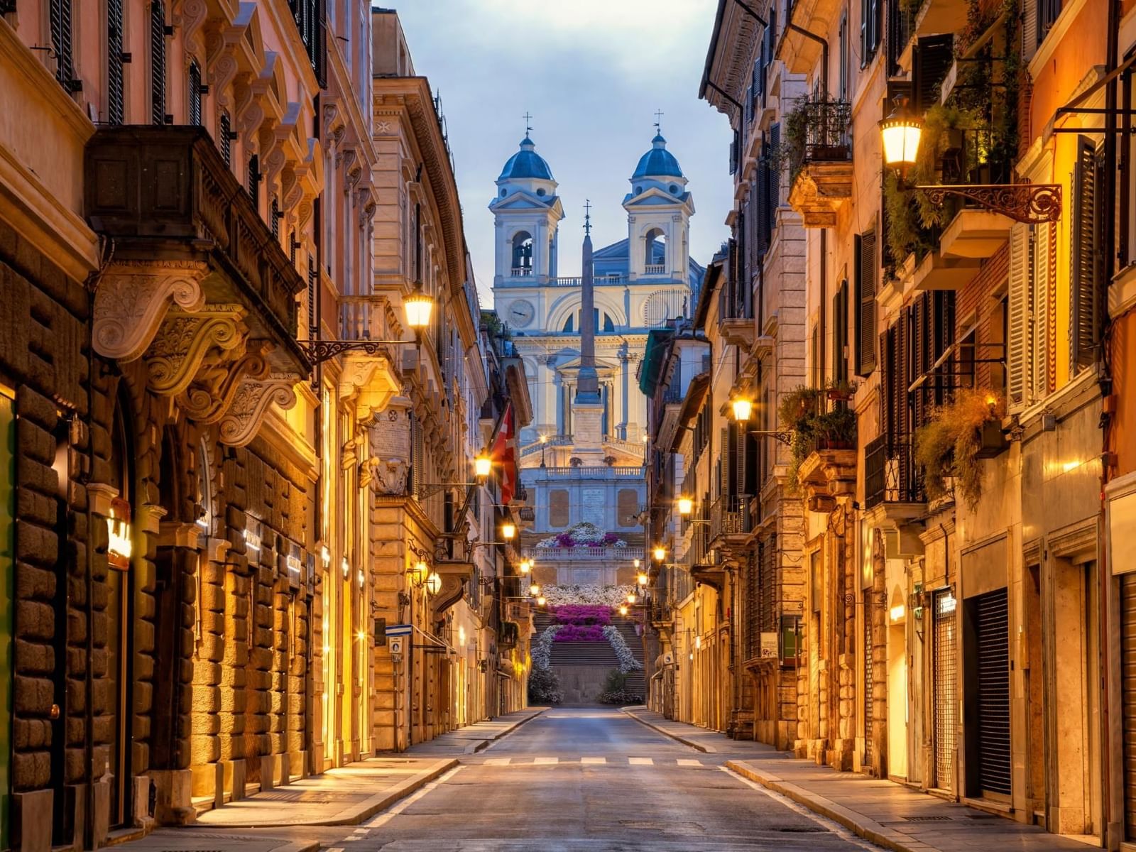 Quiet Via dei Condotti street with historic buildings, leading to a stunning church near The Guardian Hotel