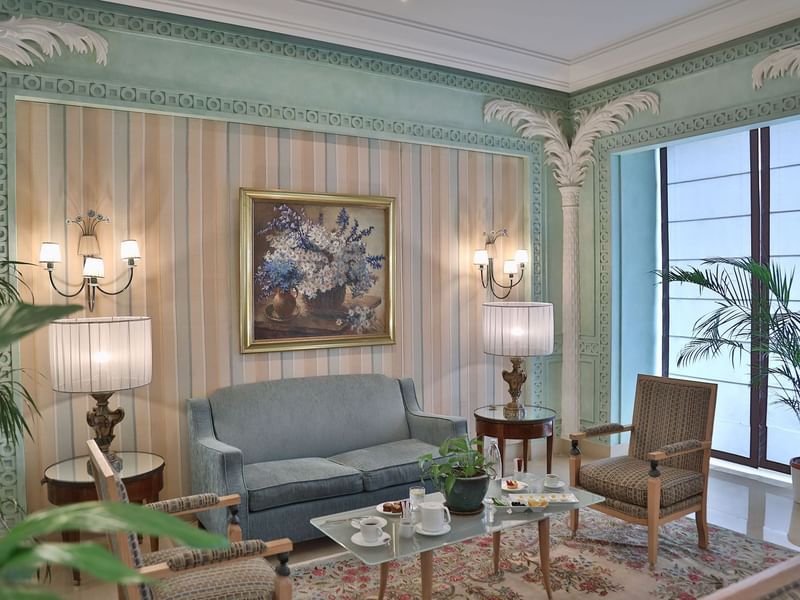 غرفة جلوس أنيقة بجدران مخططة ولوحة زهور ومصابيح جدارية وطاولة قهوة في Warwick Palm Beach Beirut Beyrouth