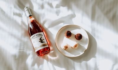 Rose Wine & plate of macaroons on a bed at Adara Hotel
