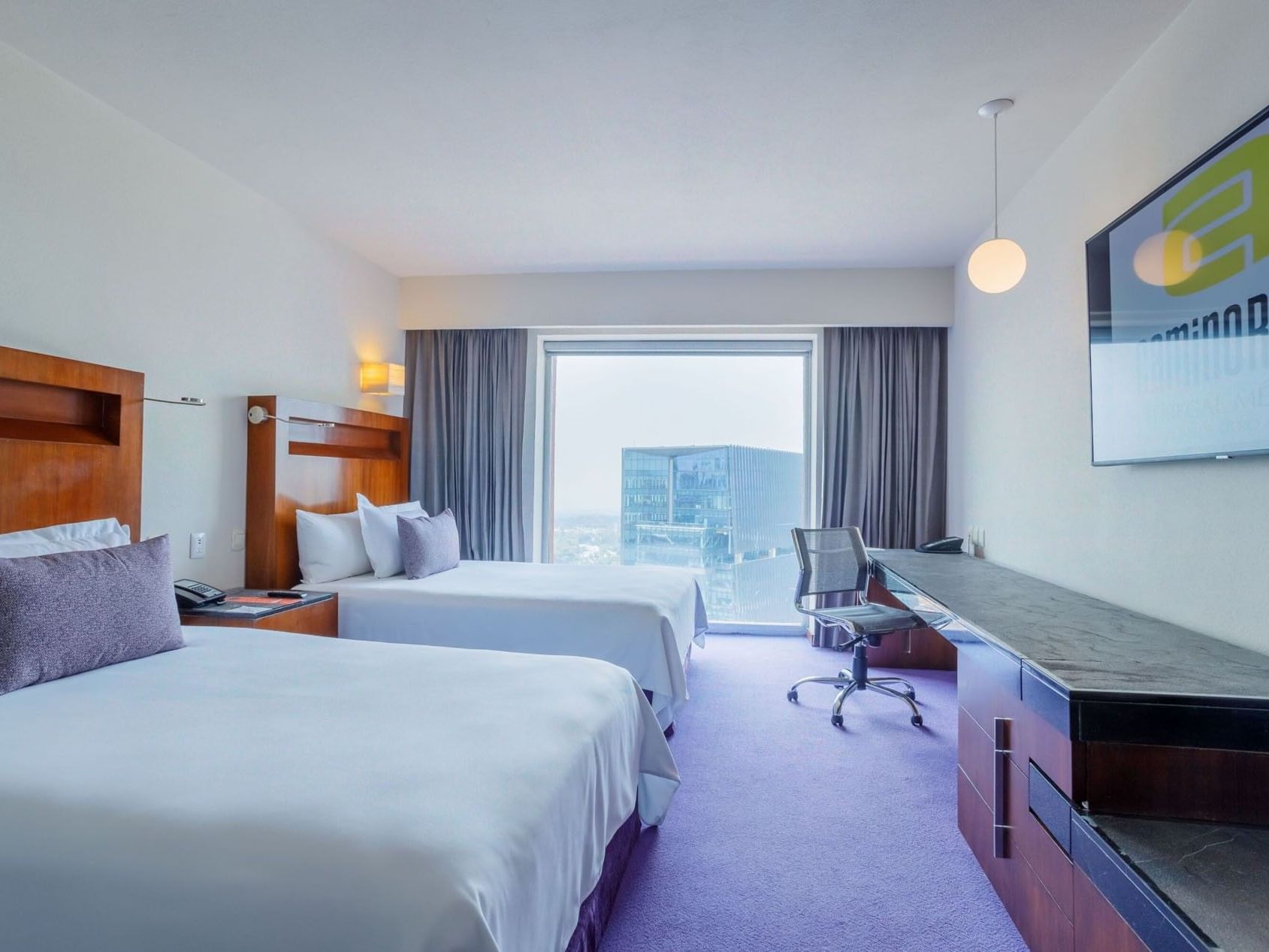 2 Double Camino Real Club with two beds, a long work desk, and a bright city window view at Camino Real Pedregal Mexico