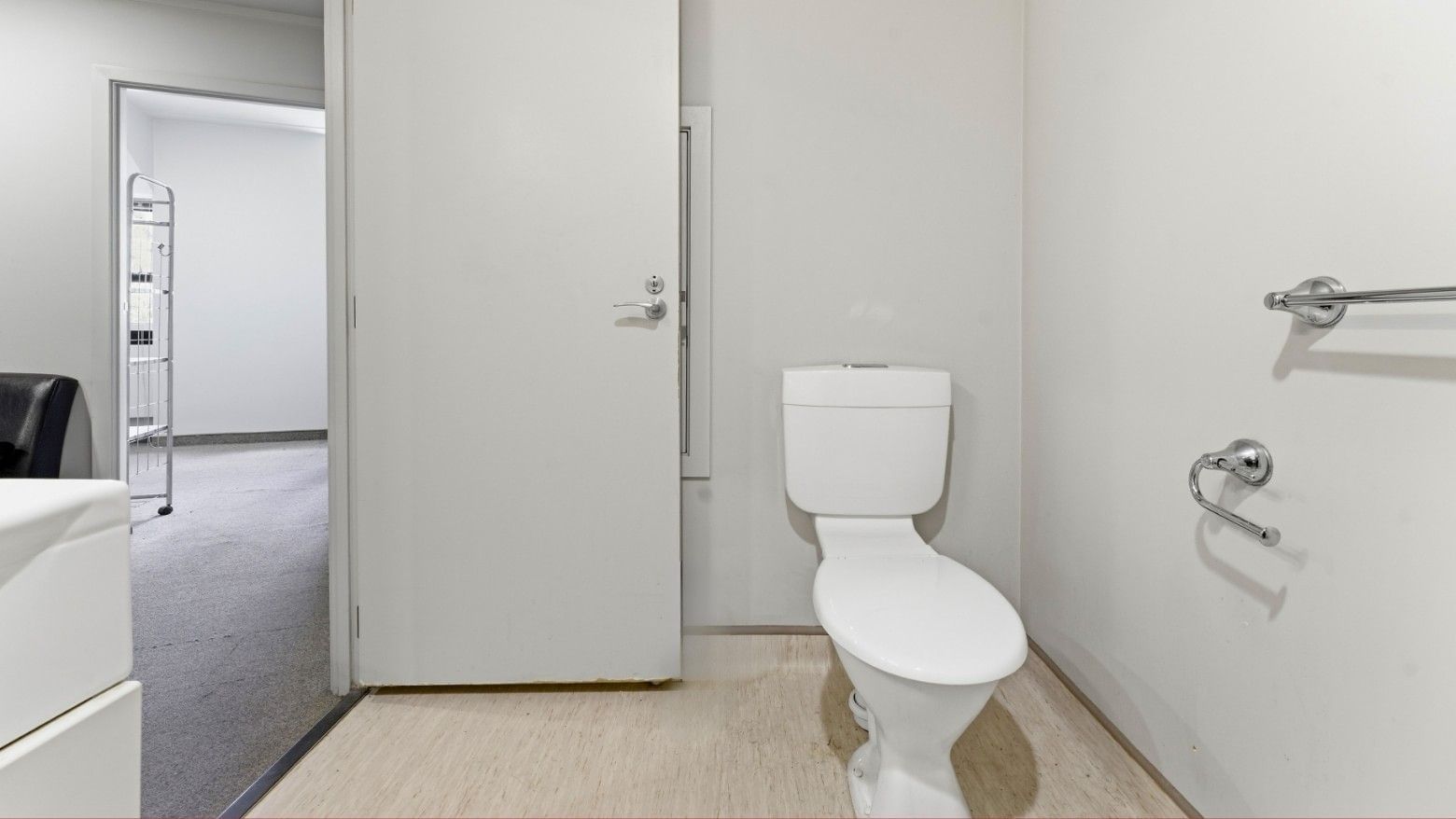 White toilet and shower area with towel bar and door at UniLodge Stafford House.
