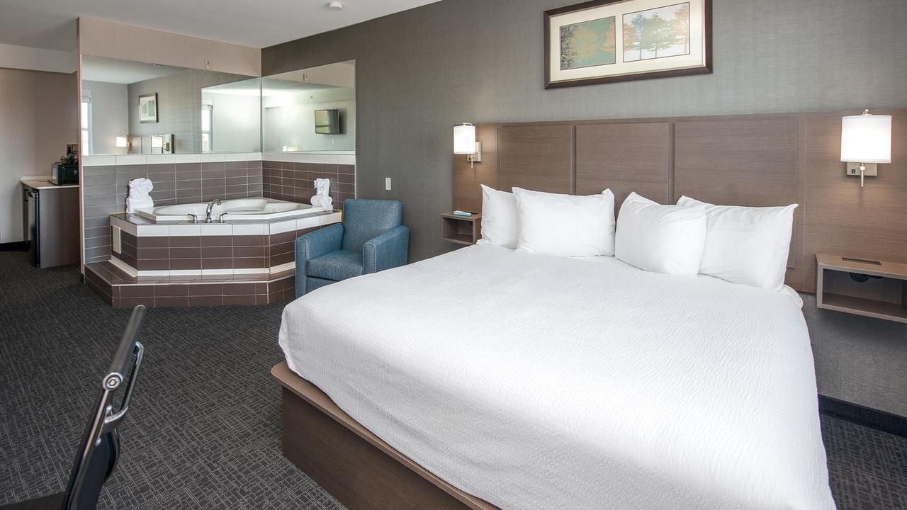 King bed, jetted tub, and chair in a hotel suite.
