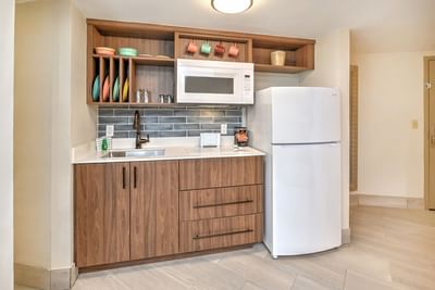 Ocean View King Kitchenette room with a refrigerator, microwave, sink, and wooden cabinets with plates and cups.