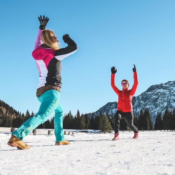 2 ladies doing yoga on a snowy land near Falkensteiner Hotels