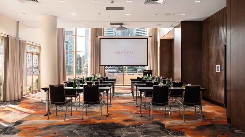 Classroom set up facing the projector screen in The Hunter Room 1-2 at Novotel Sydney on Darling Harbour