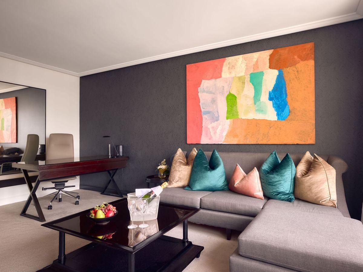 Signature Suite living area with colorful art, sofa with pillows, dark walls, and desk at Sofitel Brisbane Central