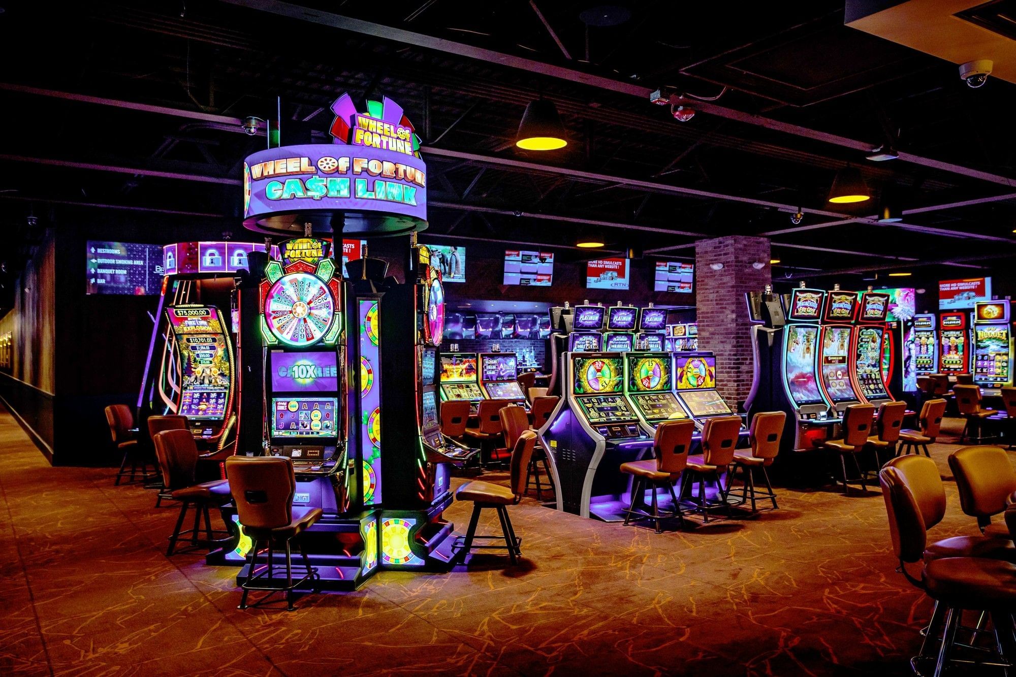 Rows of illuminated slot machines with comfortable seating inside spacious casino gaming hall venue at The Brook