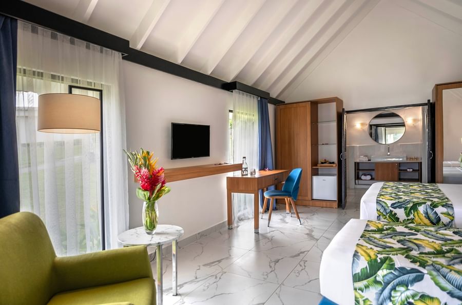 Stylish hotel room with two beds, desk, and chair at Warwick Le Lagon.