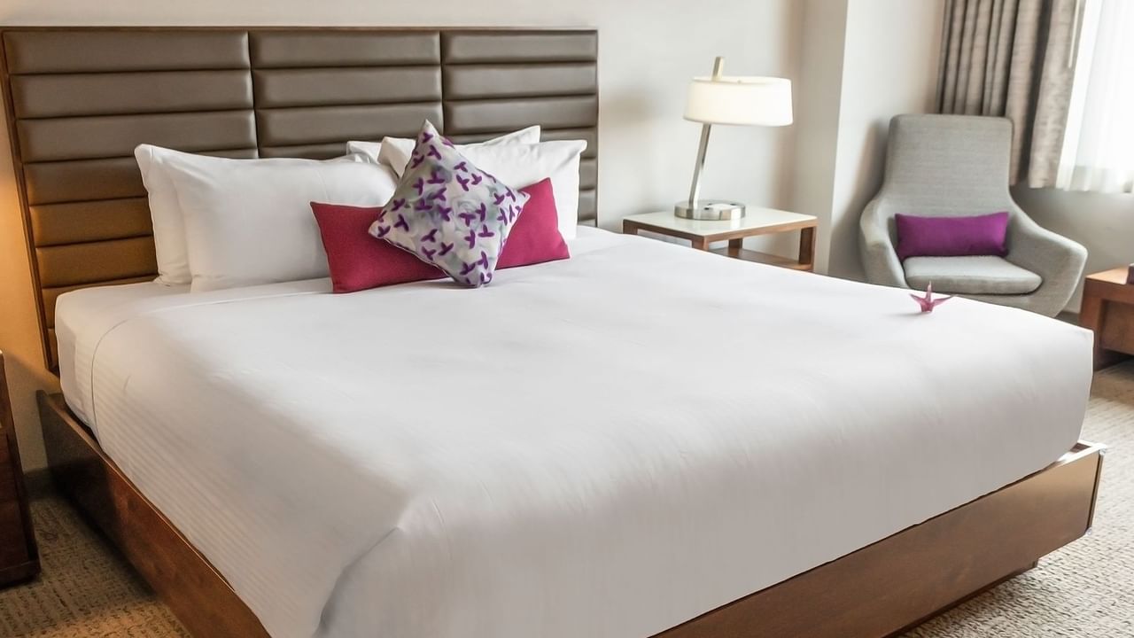 Hotel bedroom with bed, chair, lamp, and nightstand