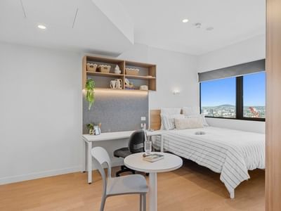 Clean modern bedroom with desk and city view at UniLodge Brisbane City.