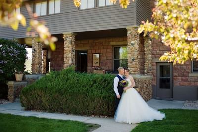 Wedding couple posing in front stoned walled building of The Ranch at Ucross, bathed in sunlight