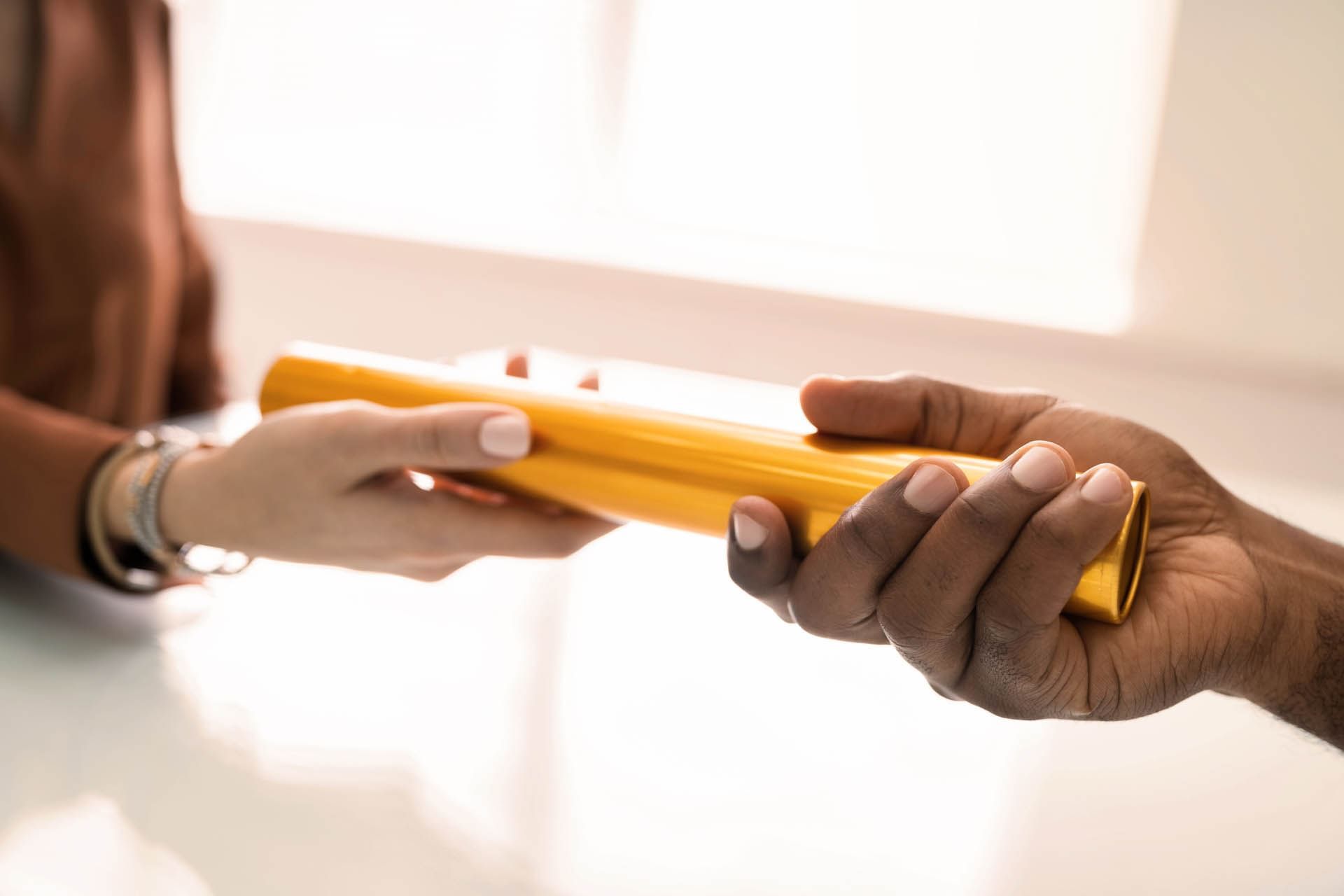 Close-up of two hands exchanging a bright yellow tube at AG Hotels