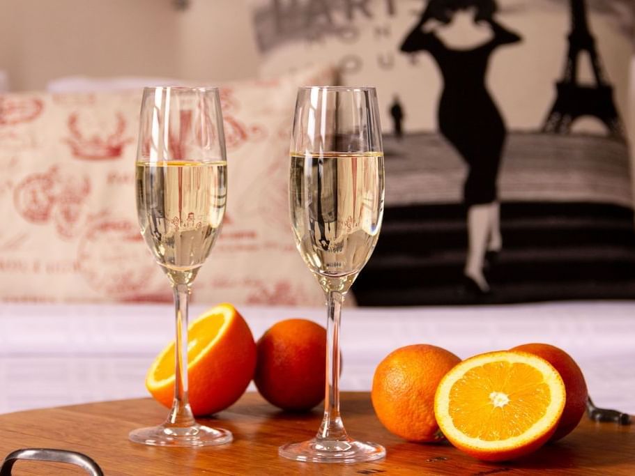2 white wine glasses & some oranges on a table at Retro Suites