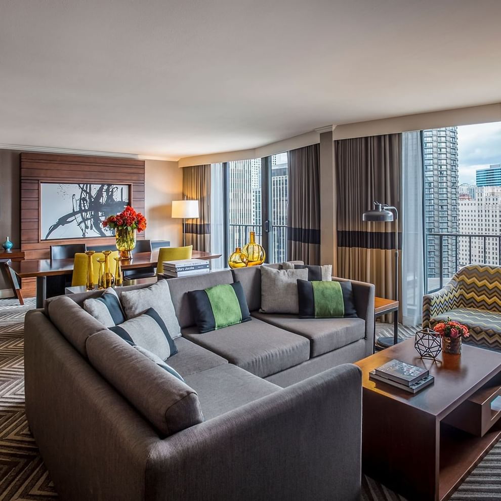 A modern living room with a gray sectional sofa, wooden coffee table, and city view.