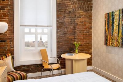 Brick wall interior, abstract painting on the wall, & window view in Queen Premiere Chardonnay at Retro Suites Hotel