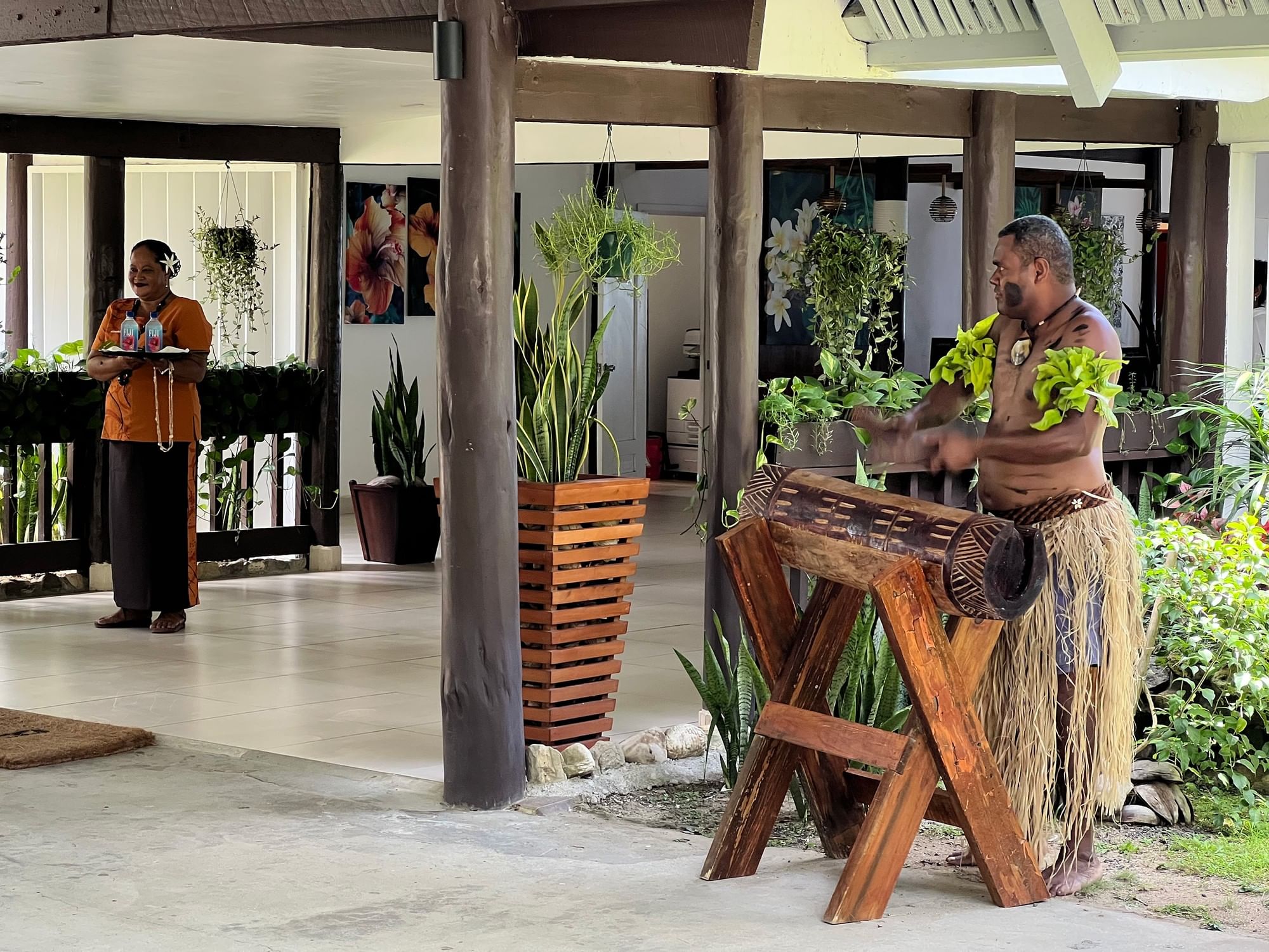 A man in traditional clothing plays a wooden instrument at Tambua Sands Beach Resort Nadi Fiji نادي.