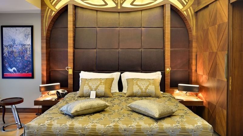 Gold patterned bed by a sofa under an ornate carved headboard in Ankara Suite with Terrace at Warwick Ankara