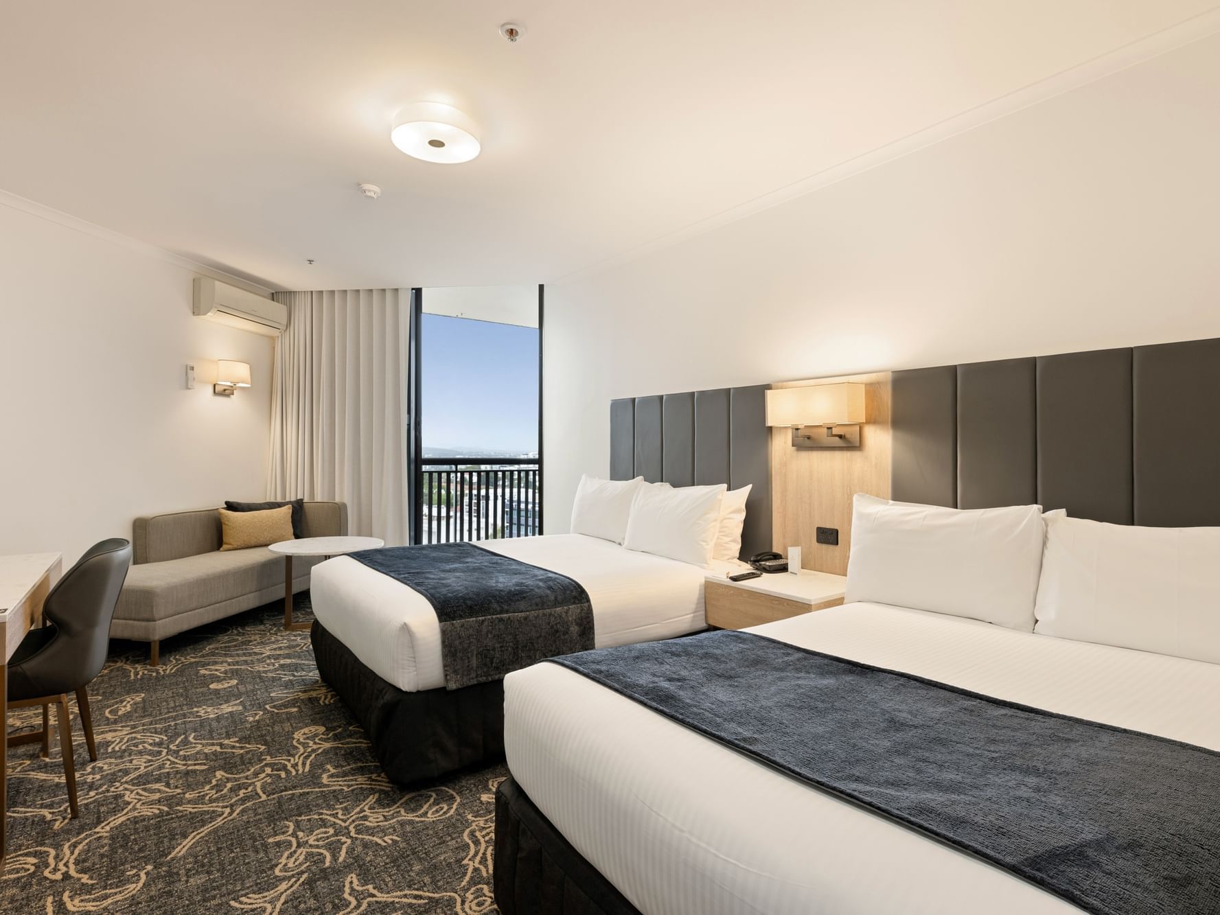 Bed with side lamp and work area in Deluxe Twin Room with balcony at Hotel Grand Chancellor Brisbane