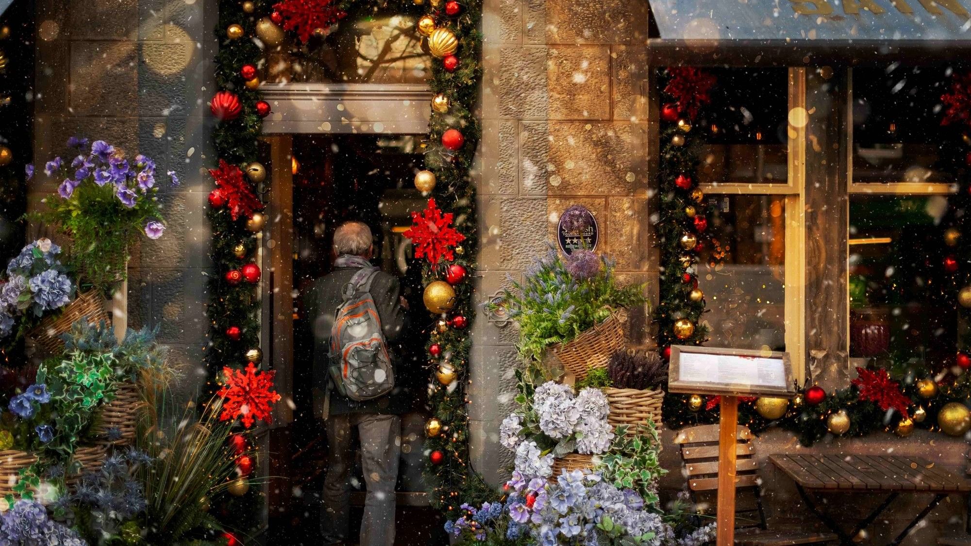 Visitor with a backpack walking into the festively decorated restaurant on a snowy evening at Seaton House
