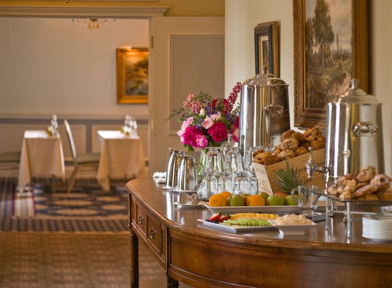 Coffee urns and pastries on a table under paintings, by flowers, and dining tables at Mountain View Grand Resort & Spa