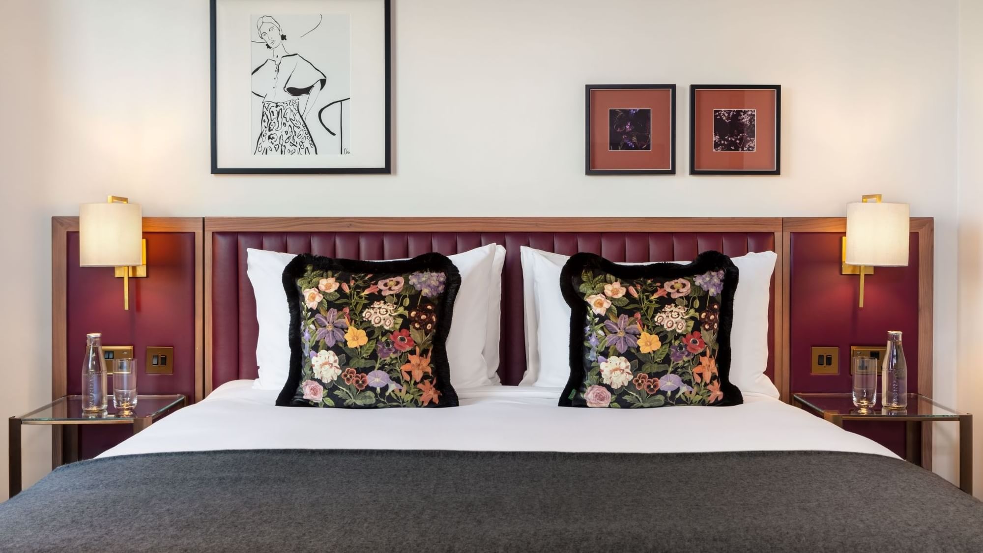 Close-up of a beautifully made bed with embroidered floral pillows in the Collection Superior Room at The May Fair Hotel