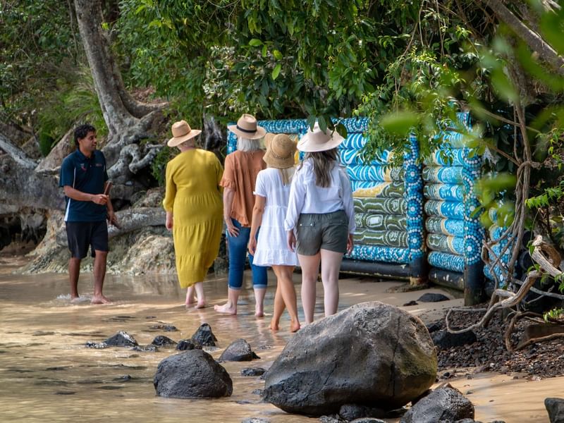 Tour group walking on a beach looking at a fence painted by First Nations artists near Sofitel Brisbane Central