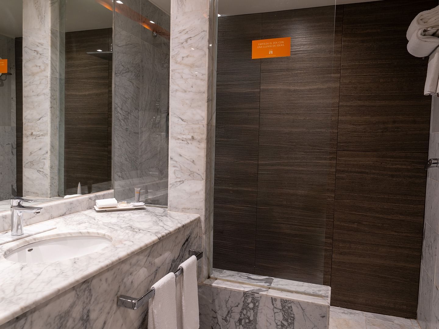 Bathroom with vanity and a dark wood-paneled walk-in shower in the King Deluxe Room at Real Inn Tijuana