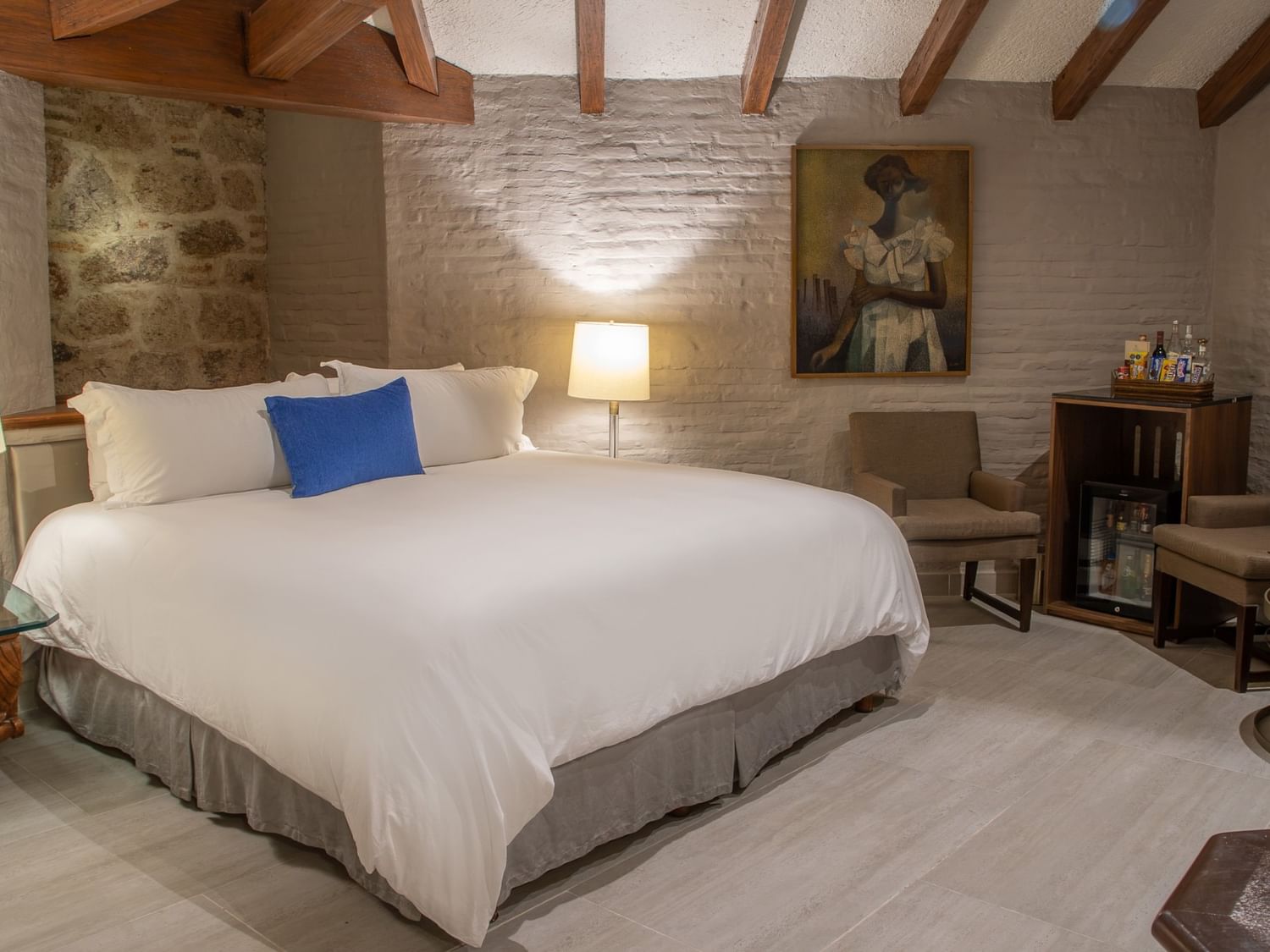 Suite Presidencial King con cama king, paredes de piedra, vigas de madera y área de estar en Quinta Real Guadalajara