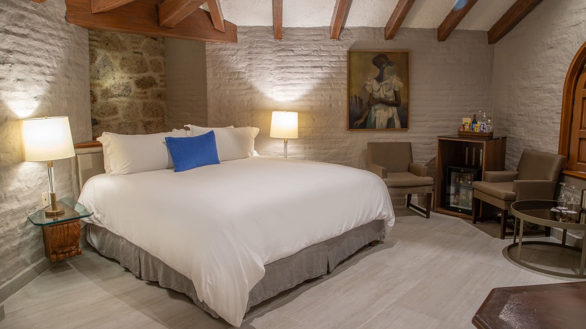 Suite Presidencial King con cama king, paredes de piedra, vigas de madera y área de estar en Quinta Real Guadalajara