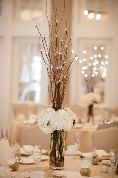 Hydrangea floral arrangement in a glass vase with twig light centerpieces on dining tables at The Simsbury Inn