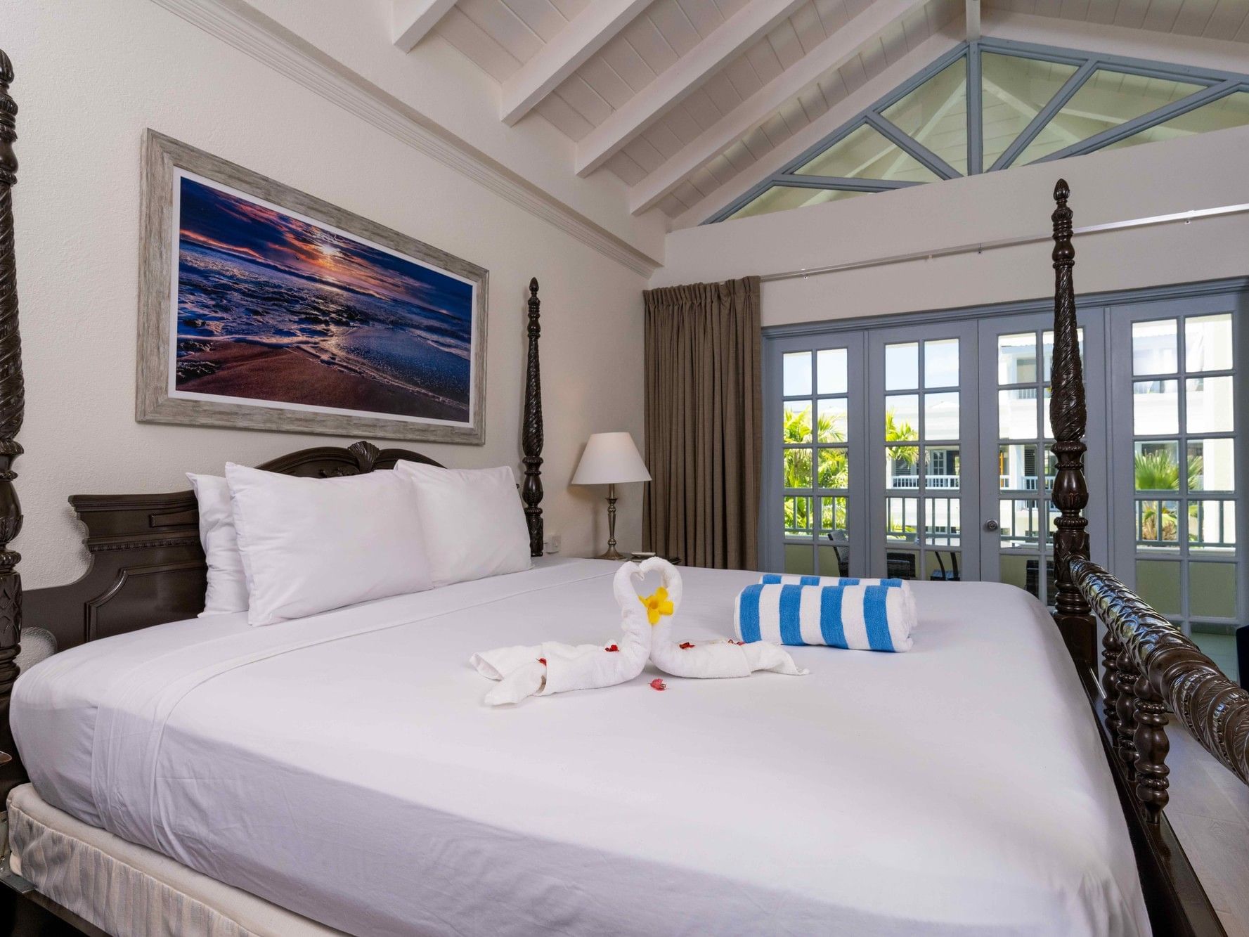 Deluxe Courtyard King room with four-poster bed, ocean artwork, and balcony doors at Savannah Beach Hotel, Bridgetown