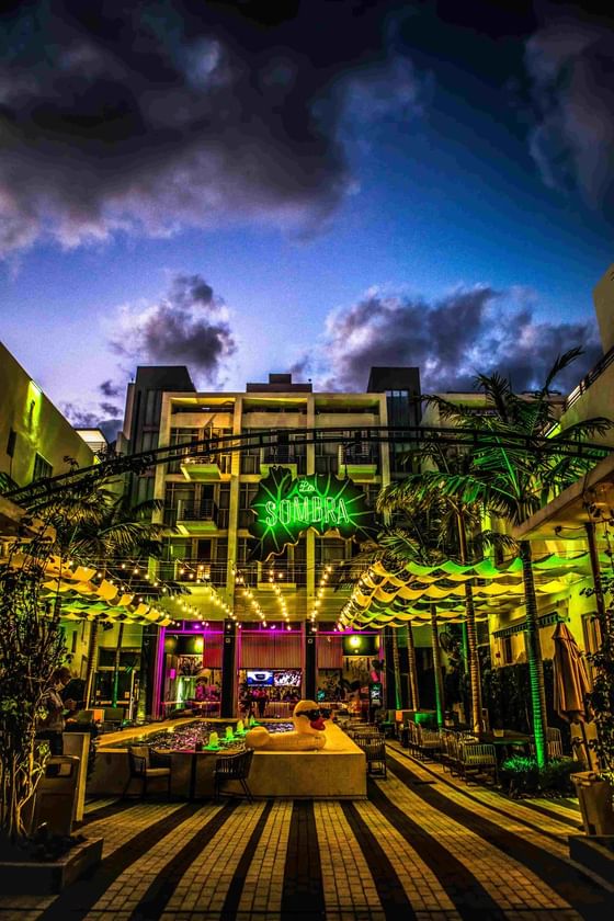 Exterior view of Fairwind Hotel Miami around with palm trees and a pond at night