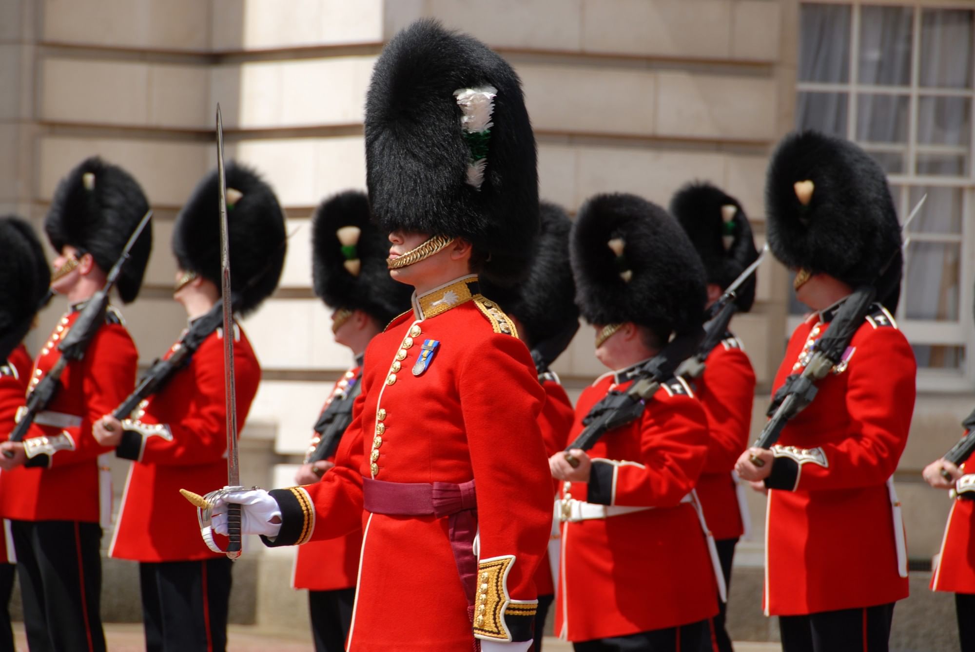 Uniformed palace guards in red jackets & black hats standing by a building near The Capital Hotel, Apartments and Townhouse