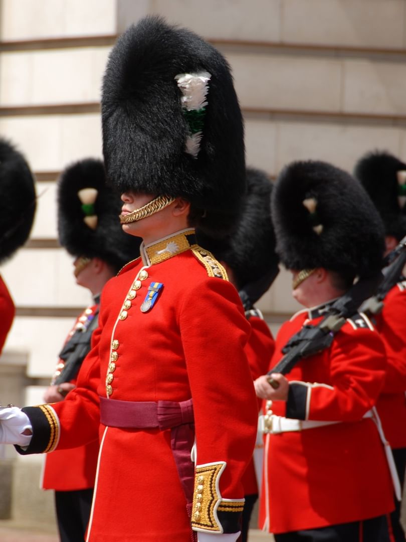 Uniformed palace guards in red jackets & black hats standing by a building near The Capital Hotel, Apartments and Townhouse