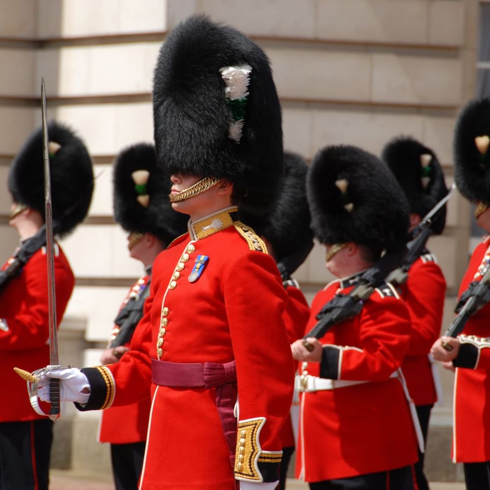 Uniformed palace guards in red jackets & black hats standing by a building near The Capital Hotel, Apartments and Townhouse