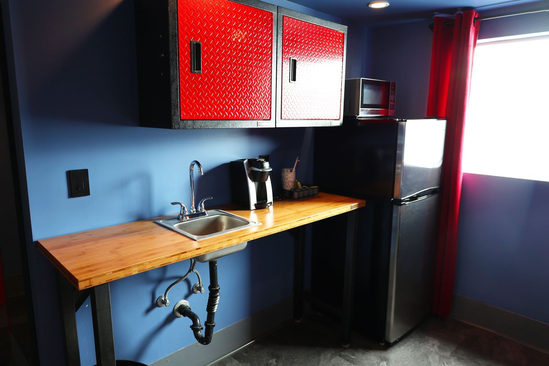 A small kitchenette with a sink, refrigerator, microwave, and coffee maker.