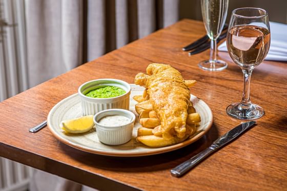 French fries with dips and a glass of wine served on a table at The Met Hotel Leeds