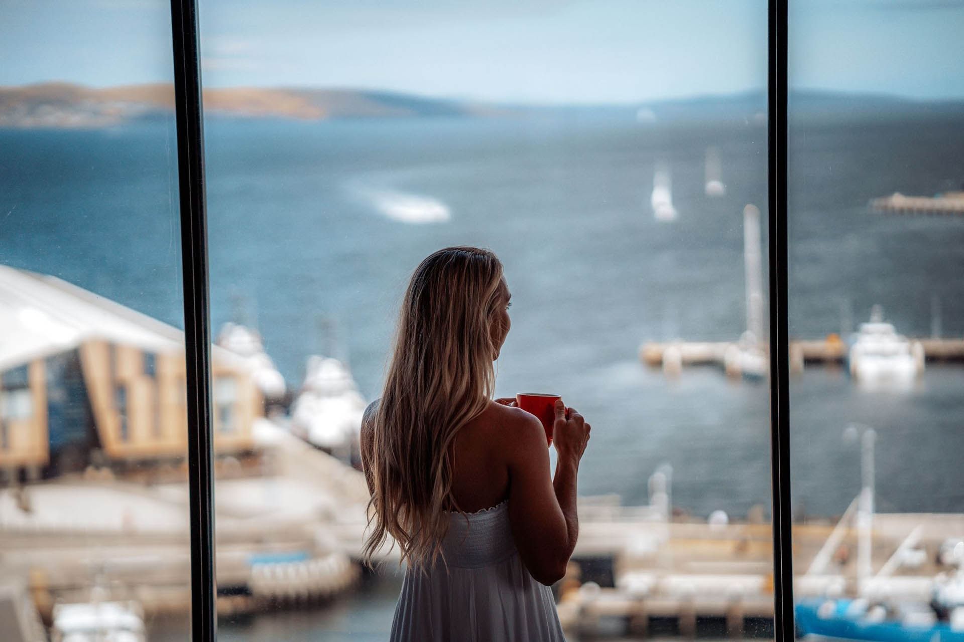 Lady overlooking dock from a window at Hotel Grand Chancellor