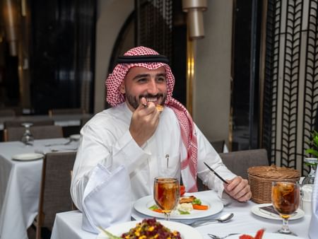 Man in traditional clothing dining at Al Duhaa Restaurant in Madinah at Saja by Warwick Madinah.