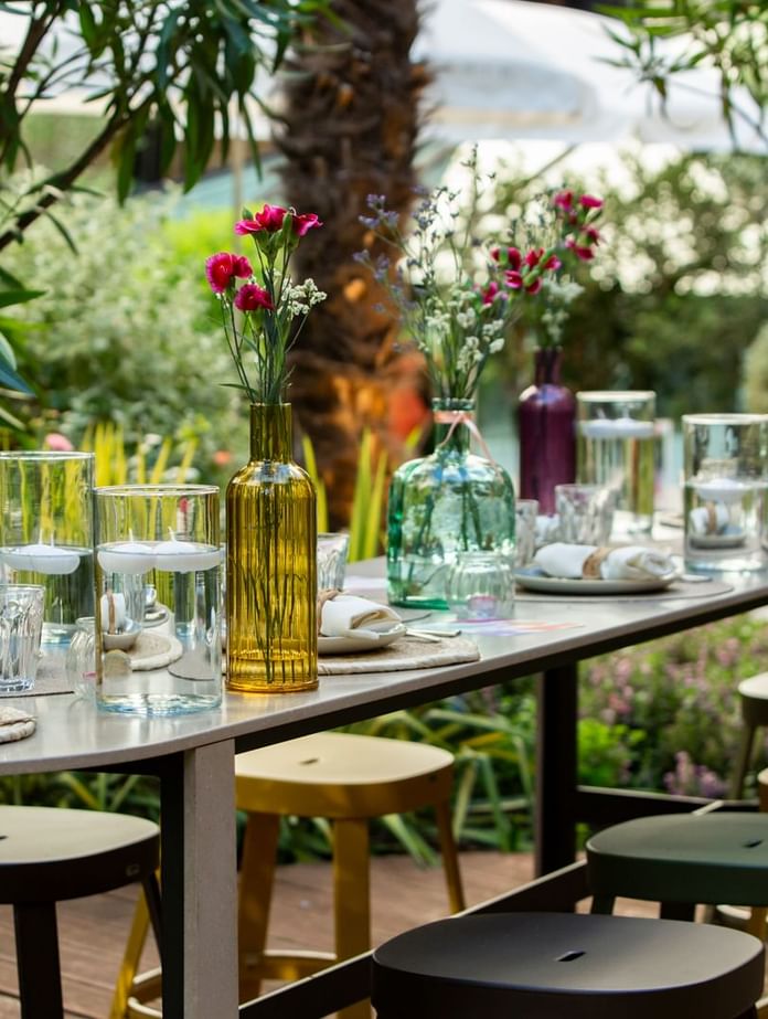 Dining table arrangement with glassware & culinary surround by trees at Oceania Hotels