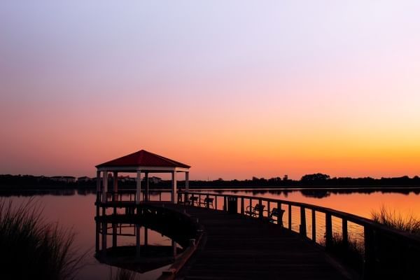 A silhouette of a dock and a pavilion on a lake at sunset. 