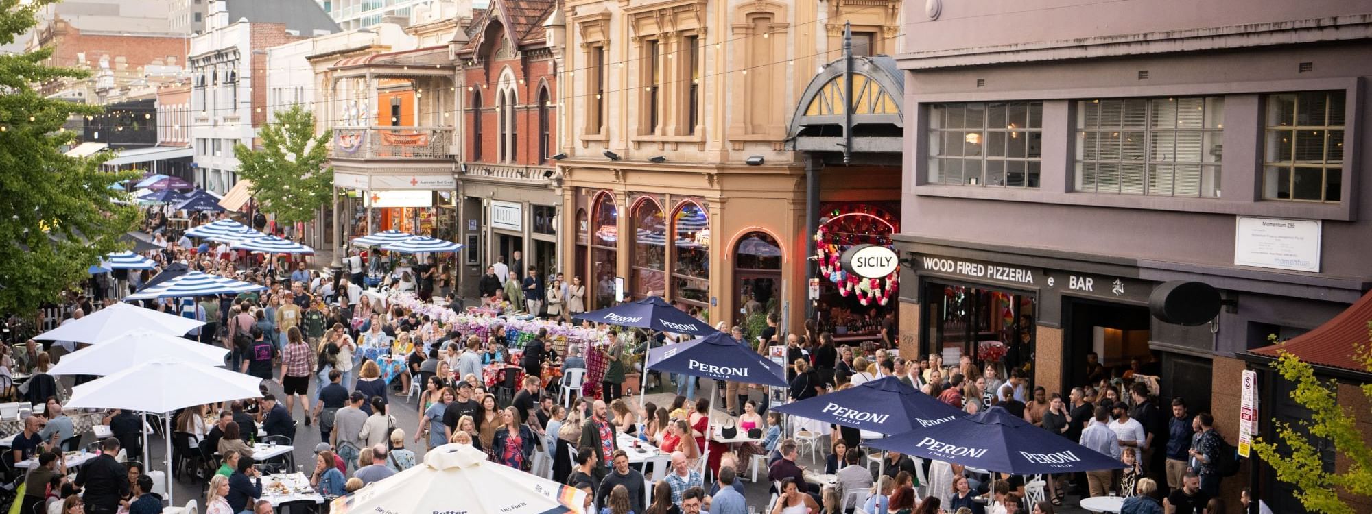 Adelaide East End, with numerous people dining outdoors under umbrellas near Ibis Adelaide