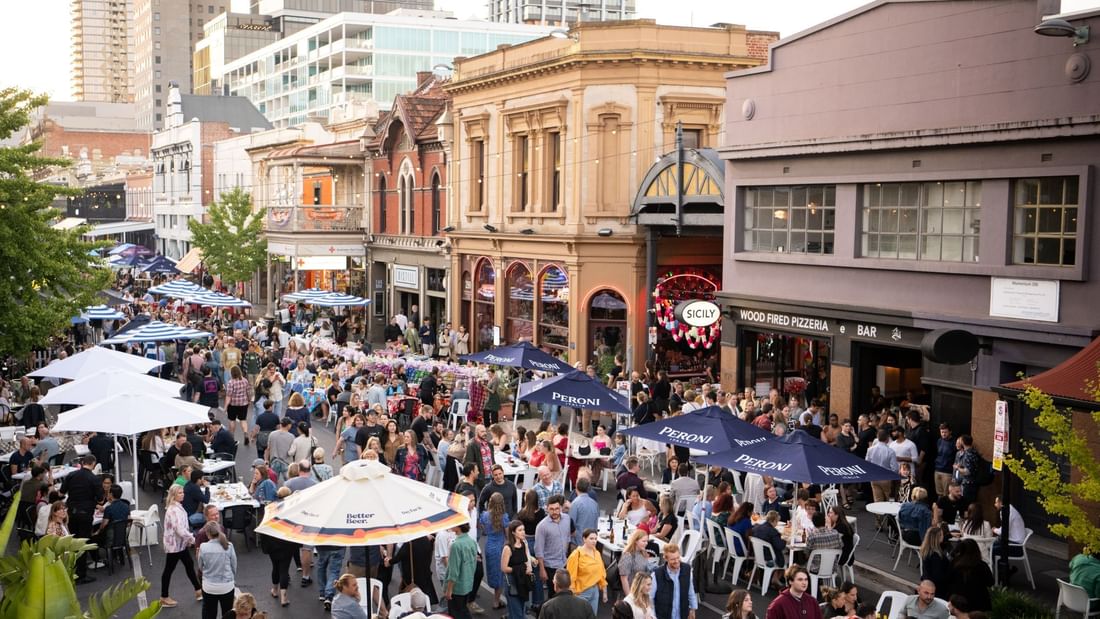 Adelaide East End, with numerous people dining outdoors under umbrellas near Ibis Adelaide