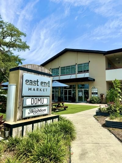 A sign outside in front of a building that reads “east end market, DOMU, and Neighbors.” A progressive date at East End Market is a romantic thing to do in Orlando.