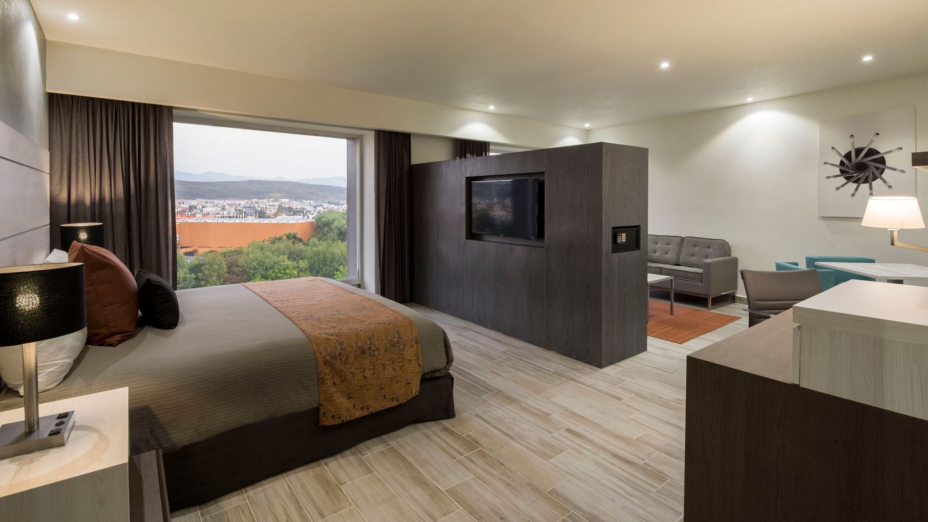King Junior Suite with a bed, brown accents, & TV on a central partition, offering city views at Real Inn San Luis Potosi