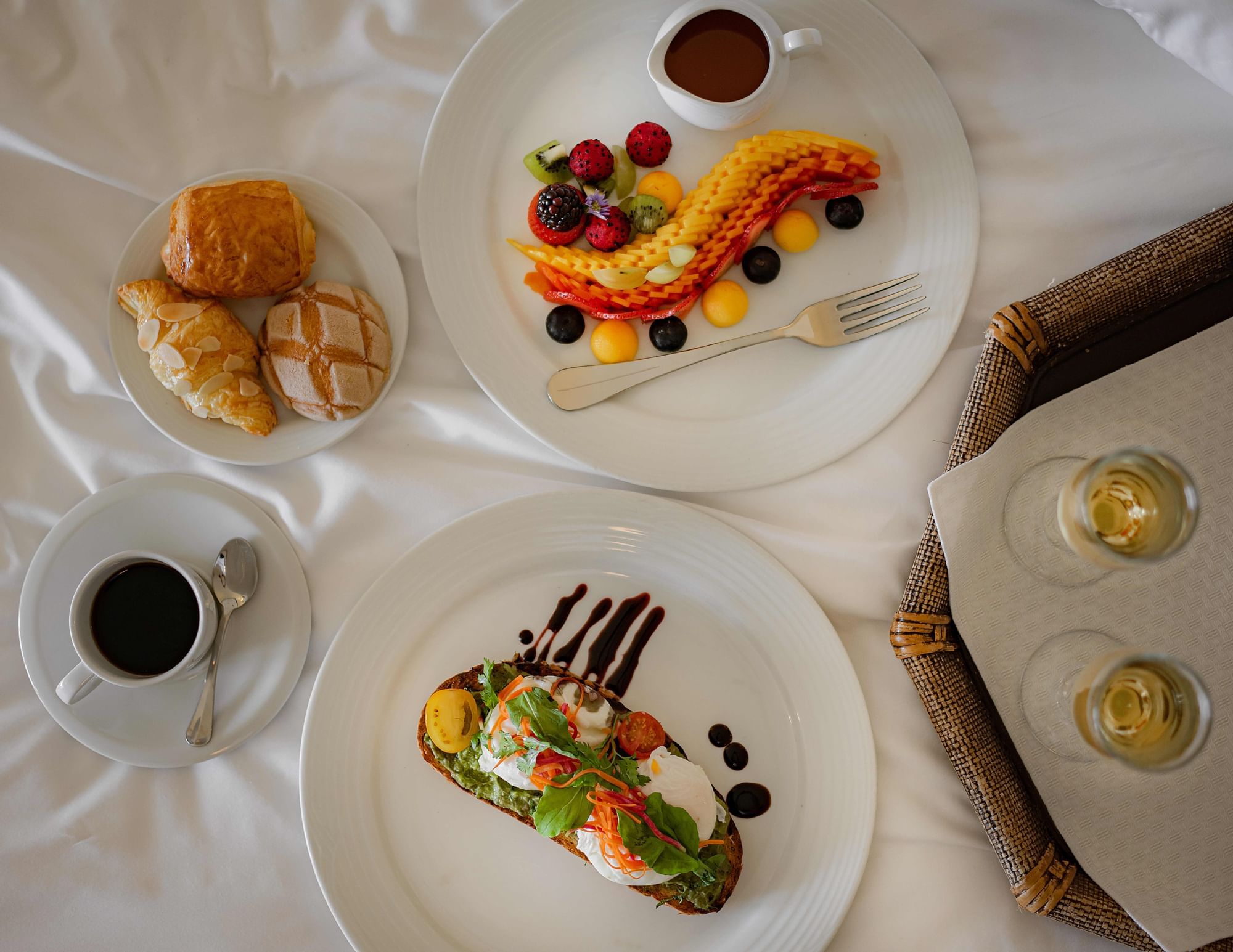 Breakfast spread featuring pastries, fresh fruit, and avocado toast with coffee at Marquis Los Cabos